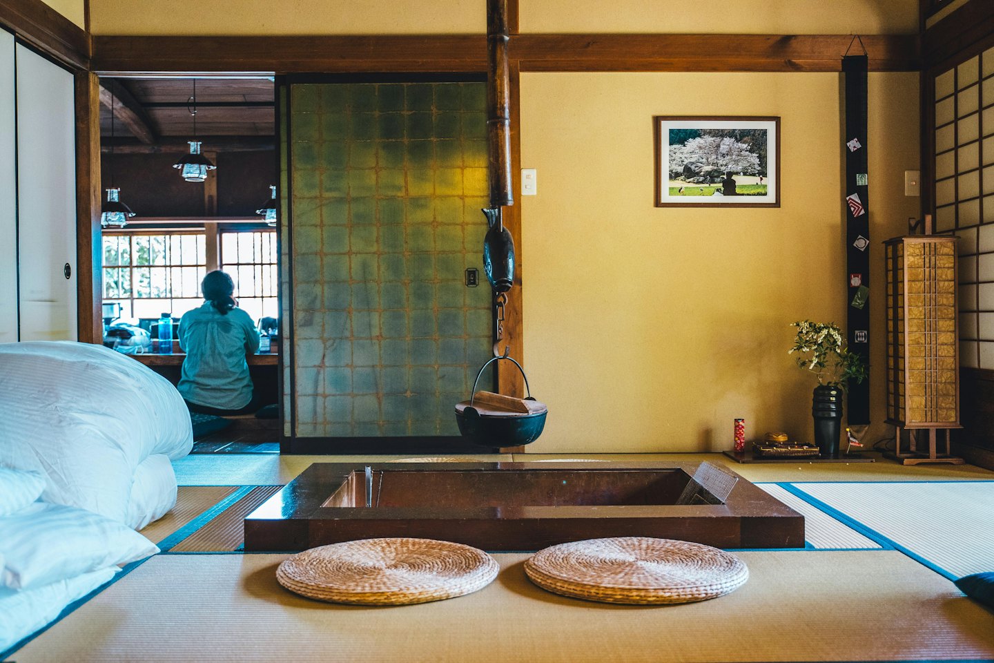 隣の部屋で囲炉裏のそばに座る人。