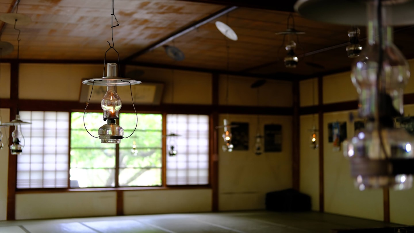畳敷きの伝統的な日本家屋を照らす吊り下げられた提灯。